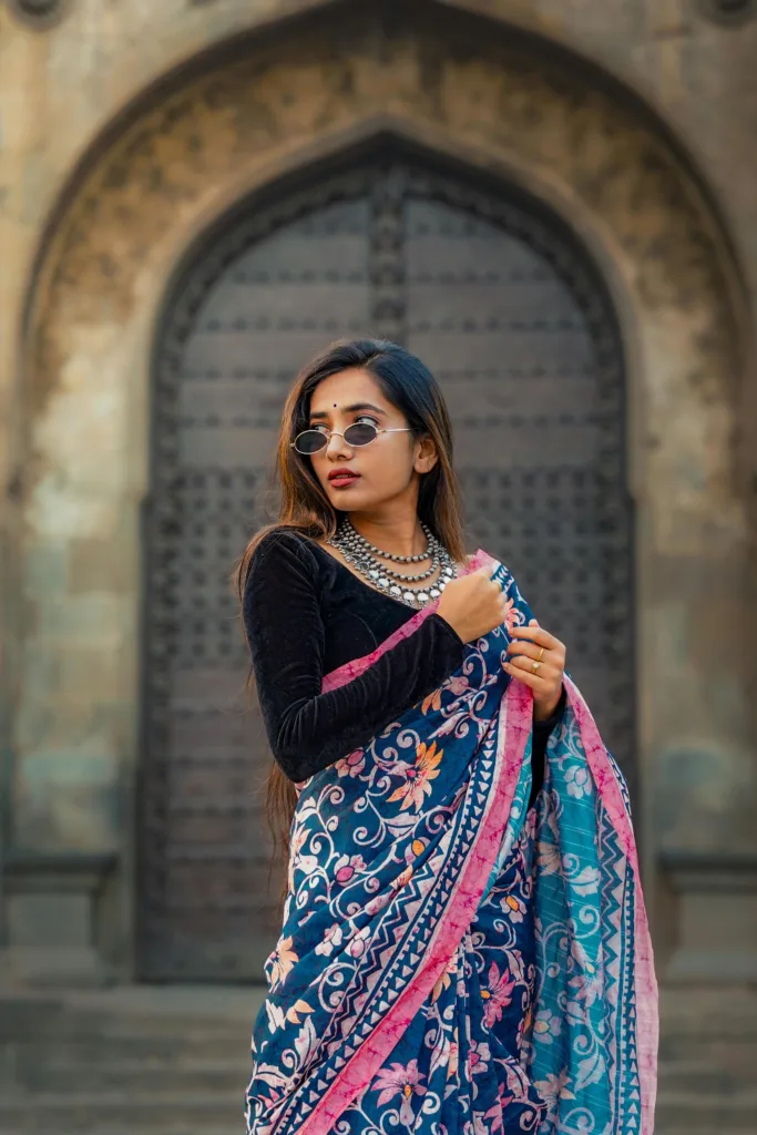 pexels-photo-27139278-27139278-1 Stylish Indian woman poses in colorful saree and jewelry against an architectural backdrop in Pune.