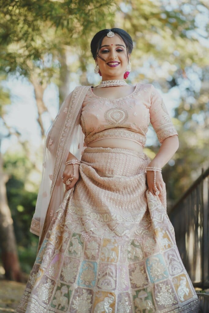 pexels-photo-15026768-15026768-1 A beautiful bride smiling in her exquisite Indian dress during a sunny outdoor wedding.