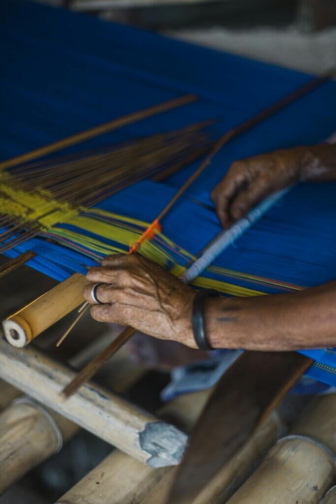pexels-photo-3585856-3585856 Close-up of hands weaving vibrant fabric on a traditional loom, showcasing skilled craftsmanship.